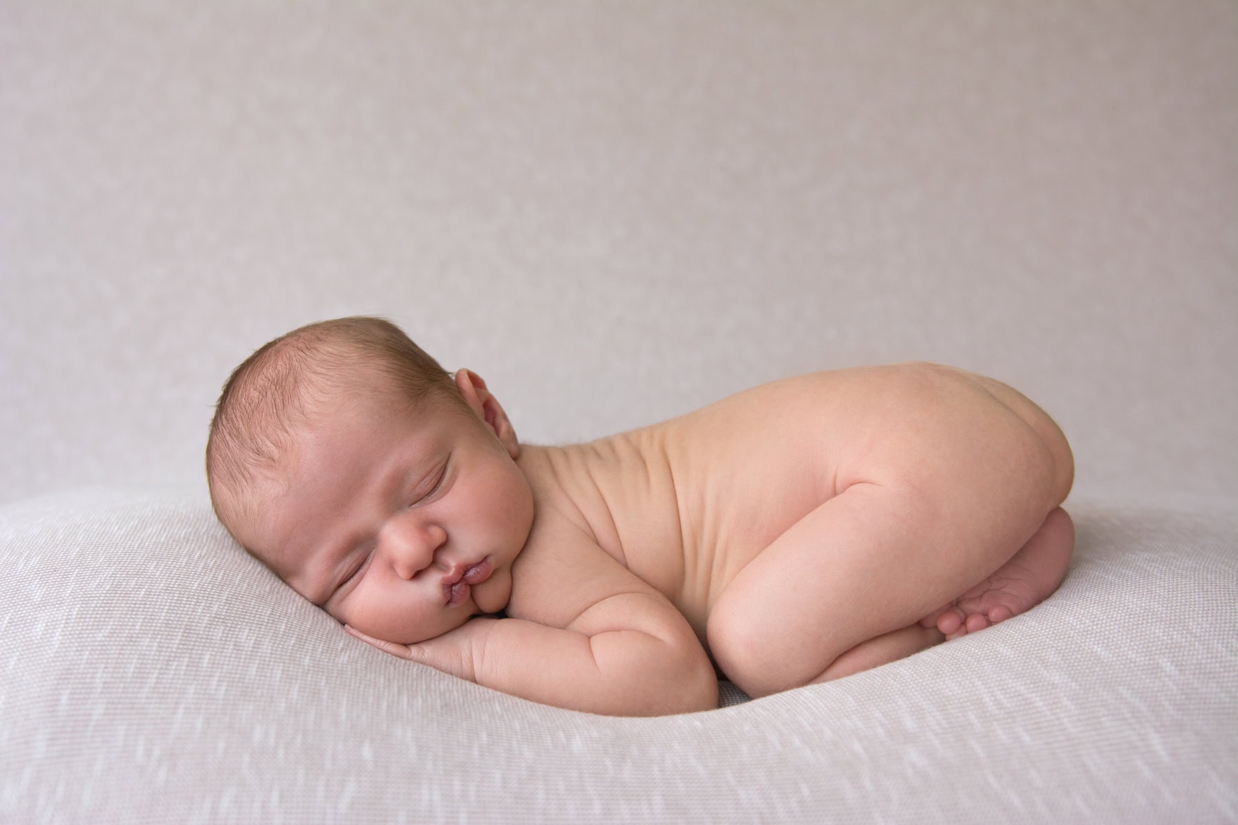 Baby sleeping peacefully on a soft, textured blanket in a cozy setting.