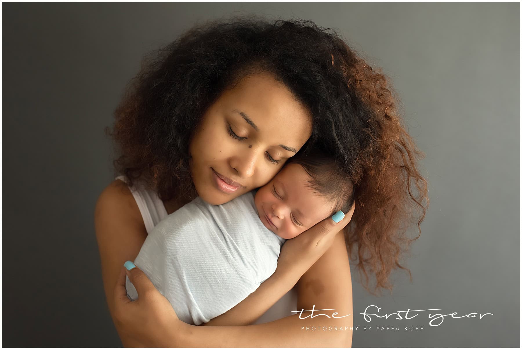 Newborn baby Alessio cuddled with mom in a studio portrait.