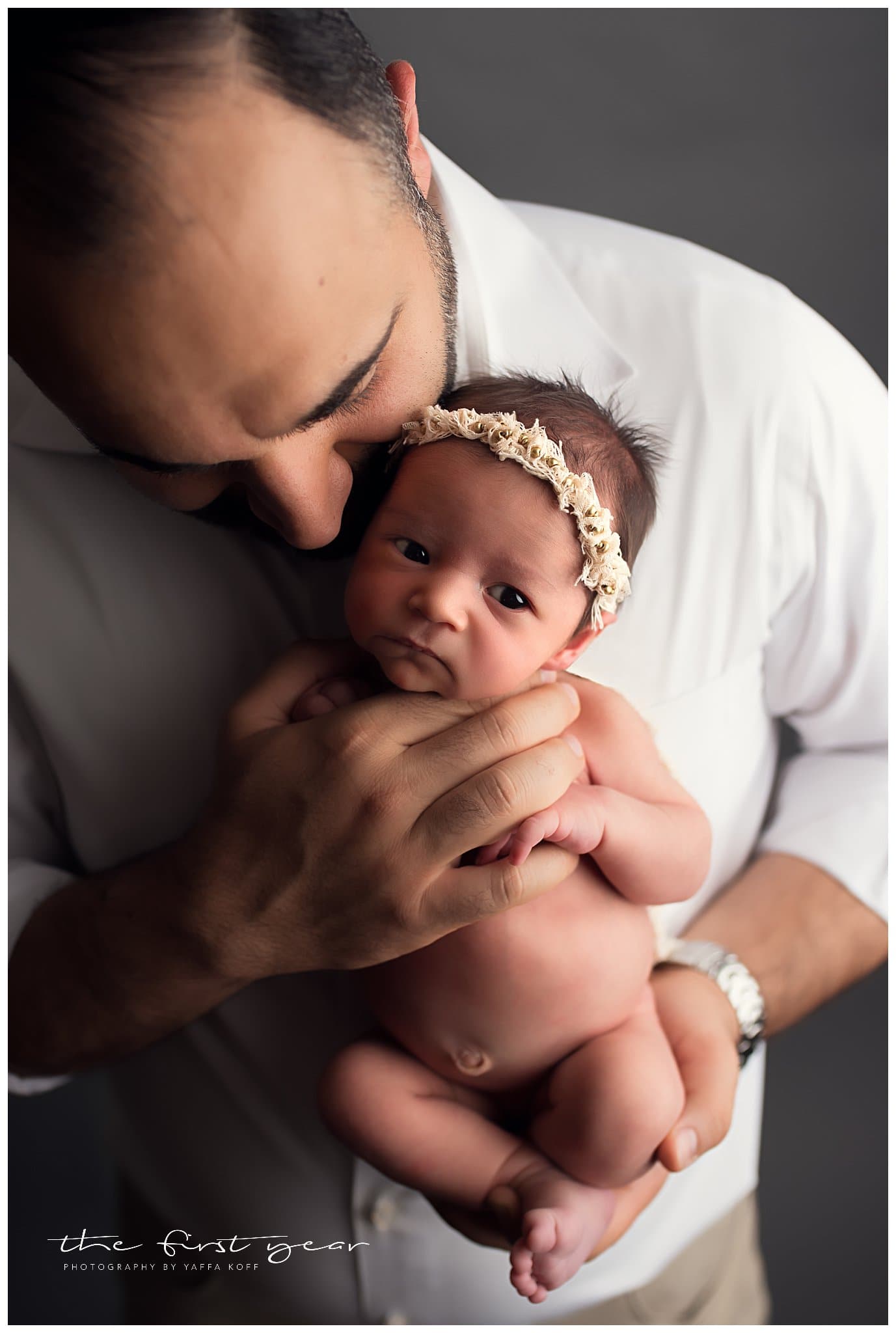 Baby girl held by father during newborn photography session.