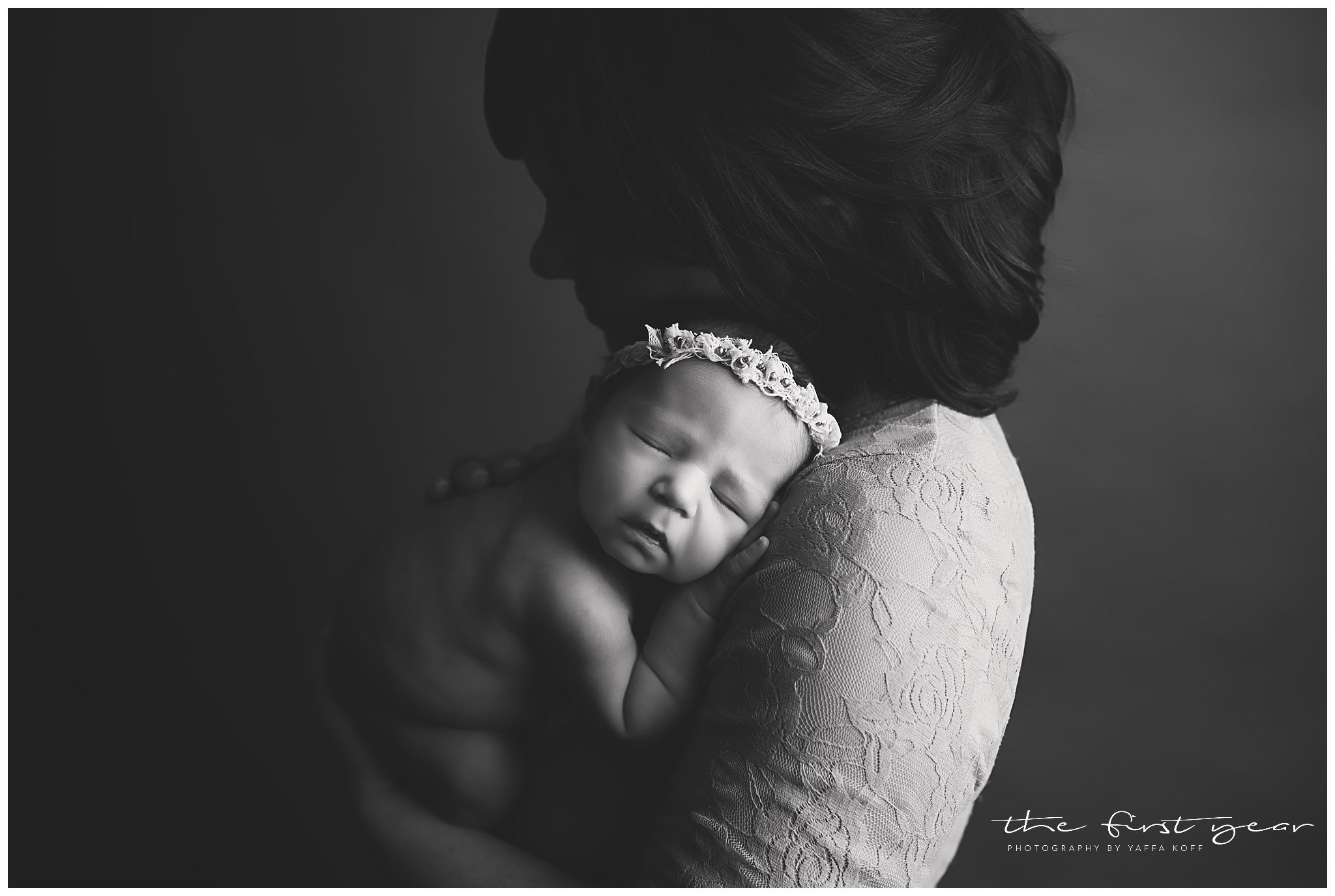 Baby girl peacefully sleeping on mom's shoulder in a black and white photo.