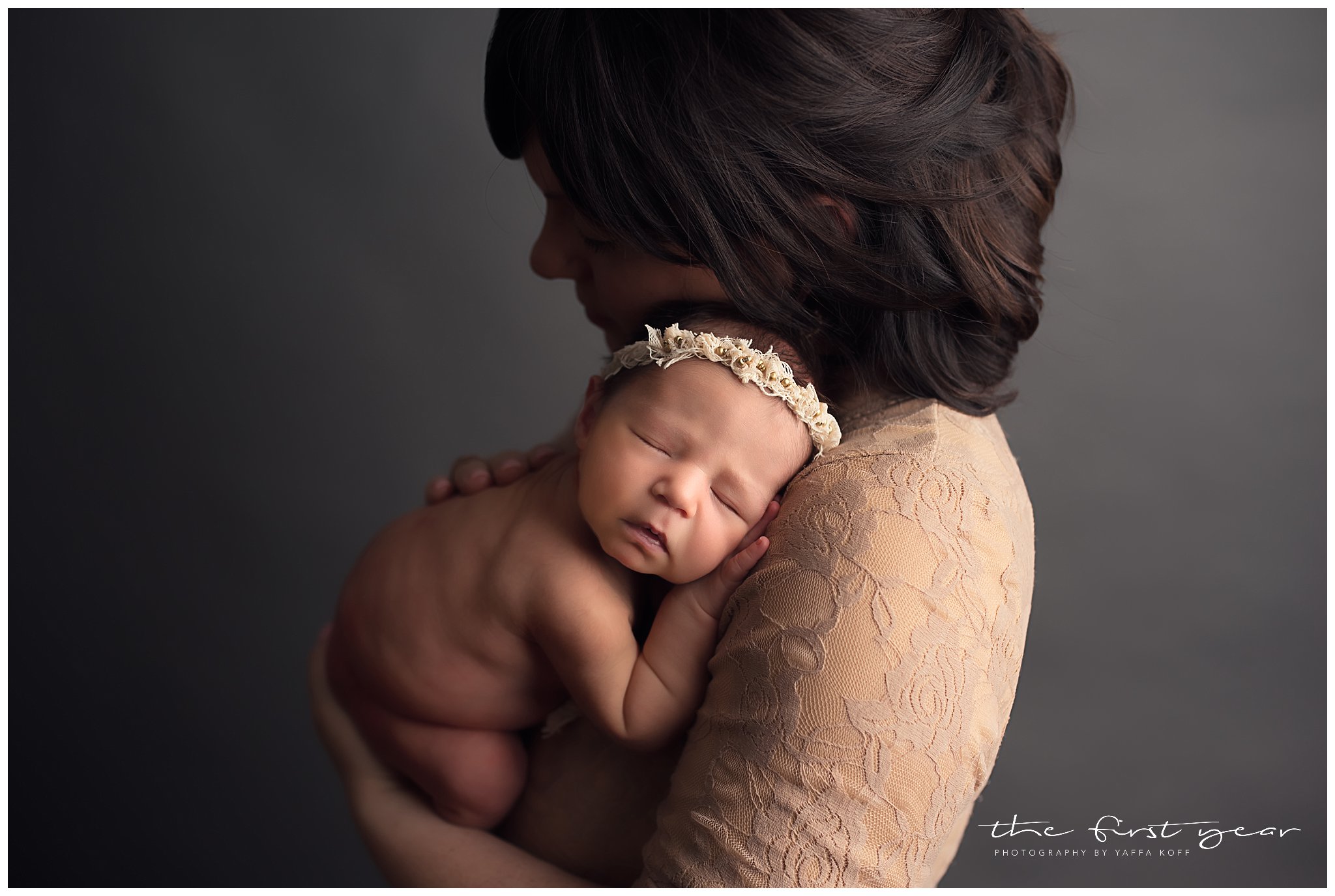 Newborn baby girl peacefully sleeping in mother's arms during a professional photoshoot.