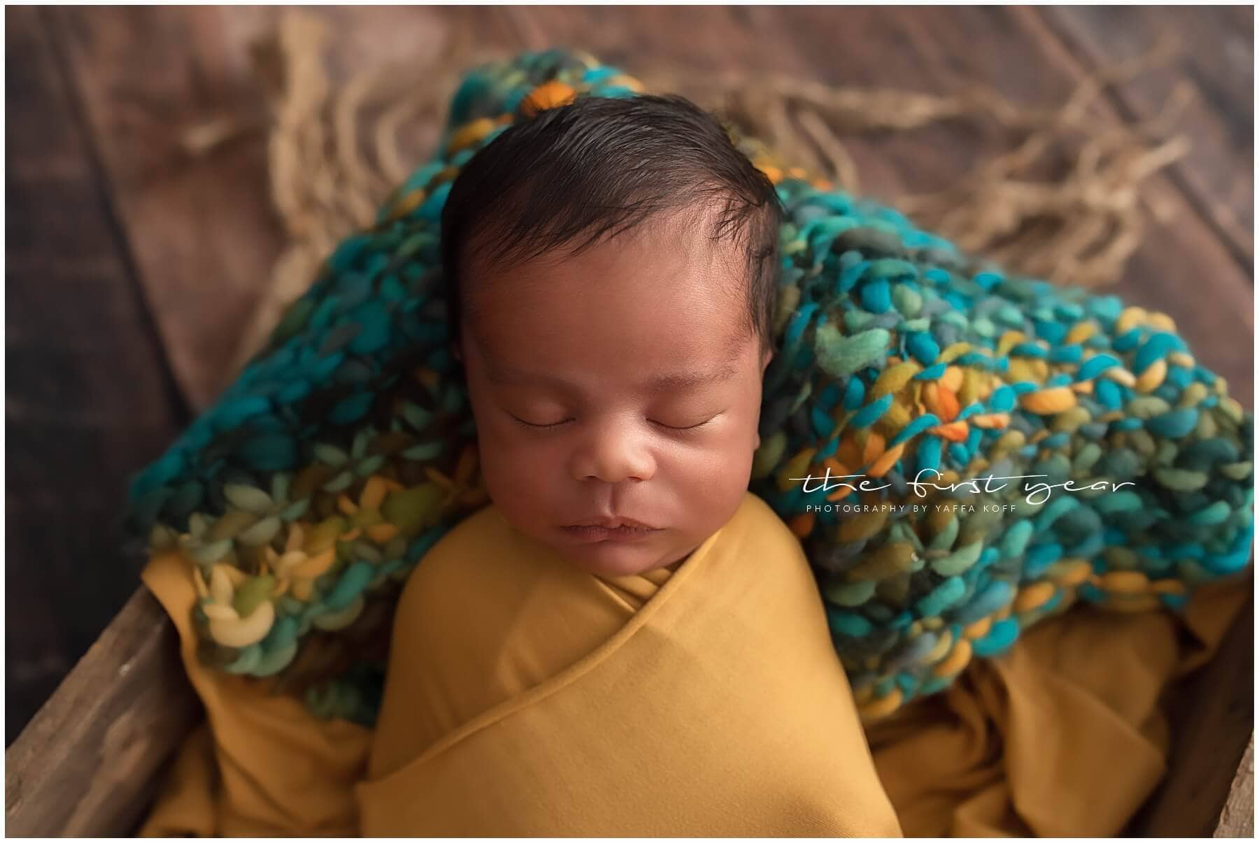 Adorable newborn baby sleeping peacefully wrapped in a yellow blanket.