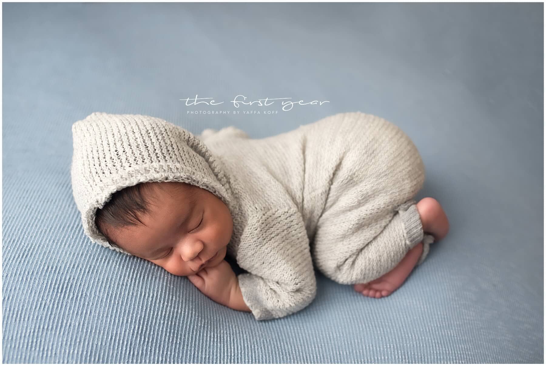 Adorable newborn baby sleeping peacefully in a cozy knit outfit.