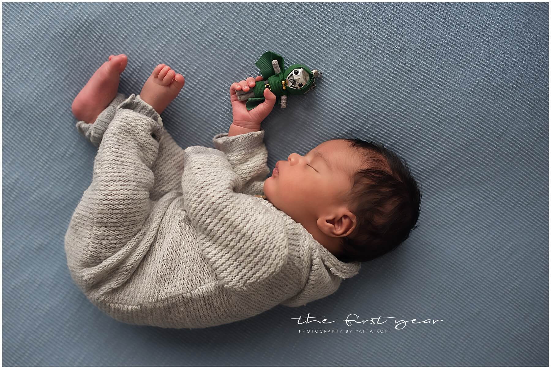 Baby Maxwell sleeping peacefully on a soft blue blanket, holding a small toy.