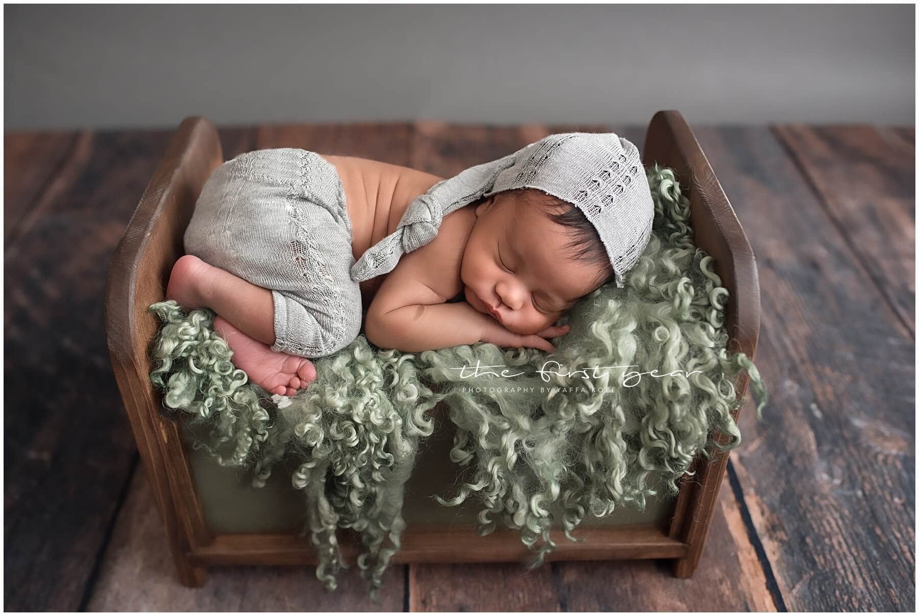 Newborn baby sleeping on a cozy bed with soft green blanket, captured during a Maryland portrait ses.