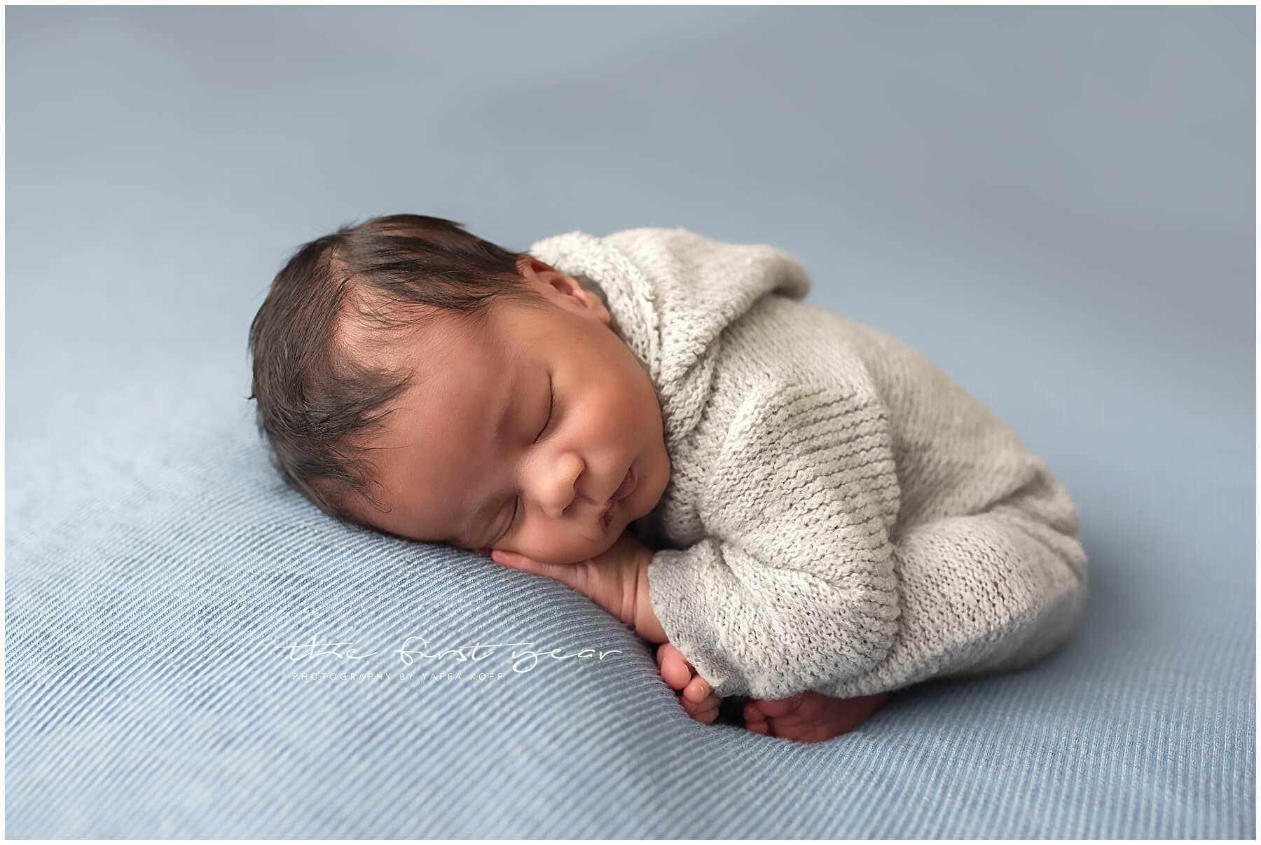 Adorable newborn sleeping peacefully on a soft blue blanket.