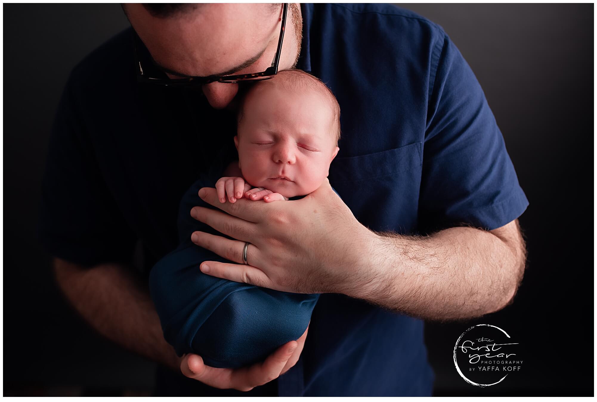 Adorable newborn baby Yehuda held by father during Maryland photoshoot.