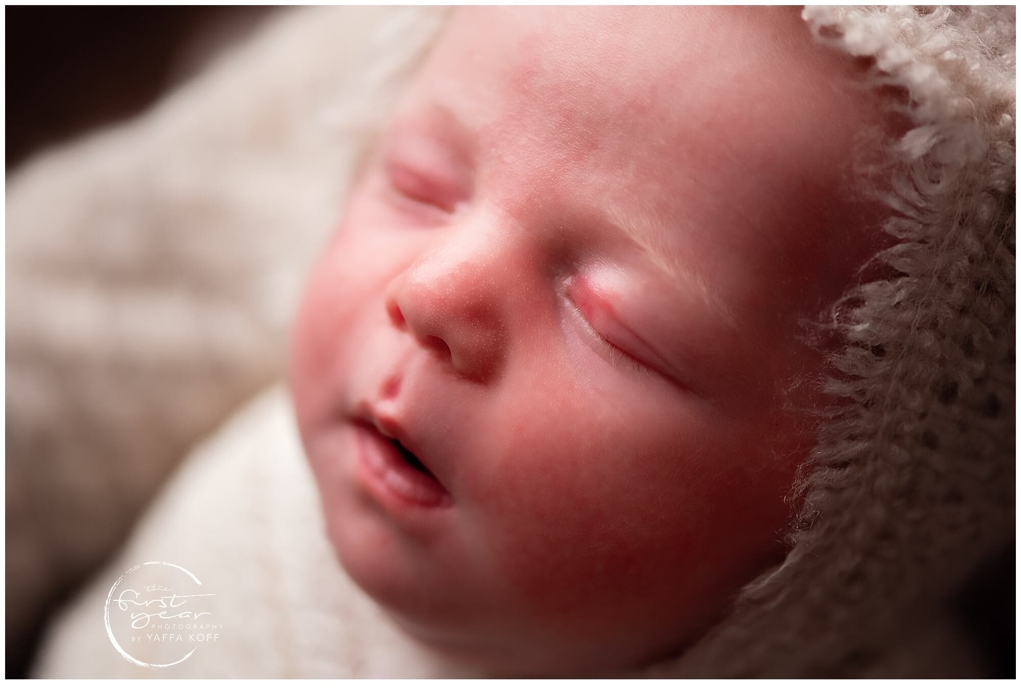 Adorable sleeping newborn baby with soft blanket and cozy hat.