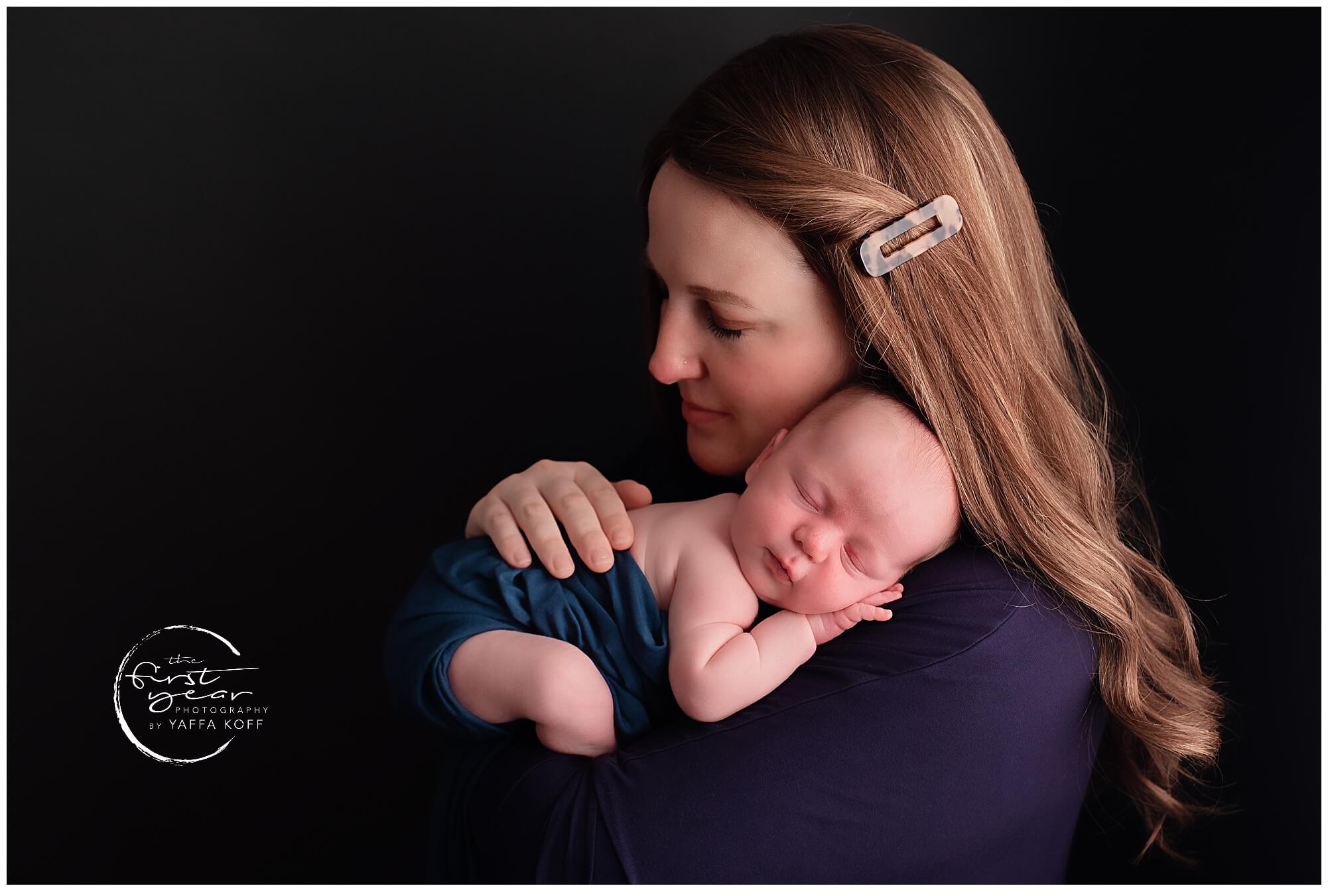 Newborn baby Yehuda peacefully sleeping in a mother's arms, captured by Maryland newborn photographe.