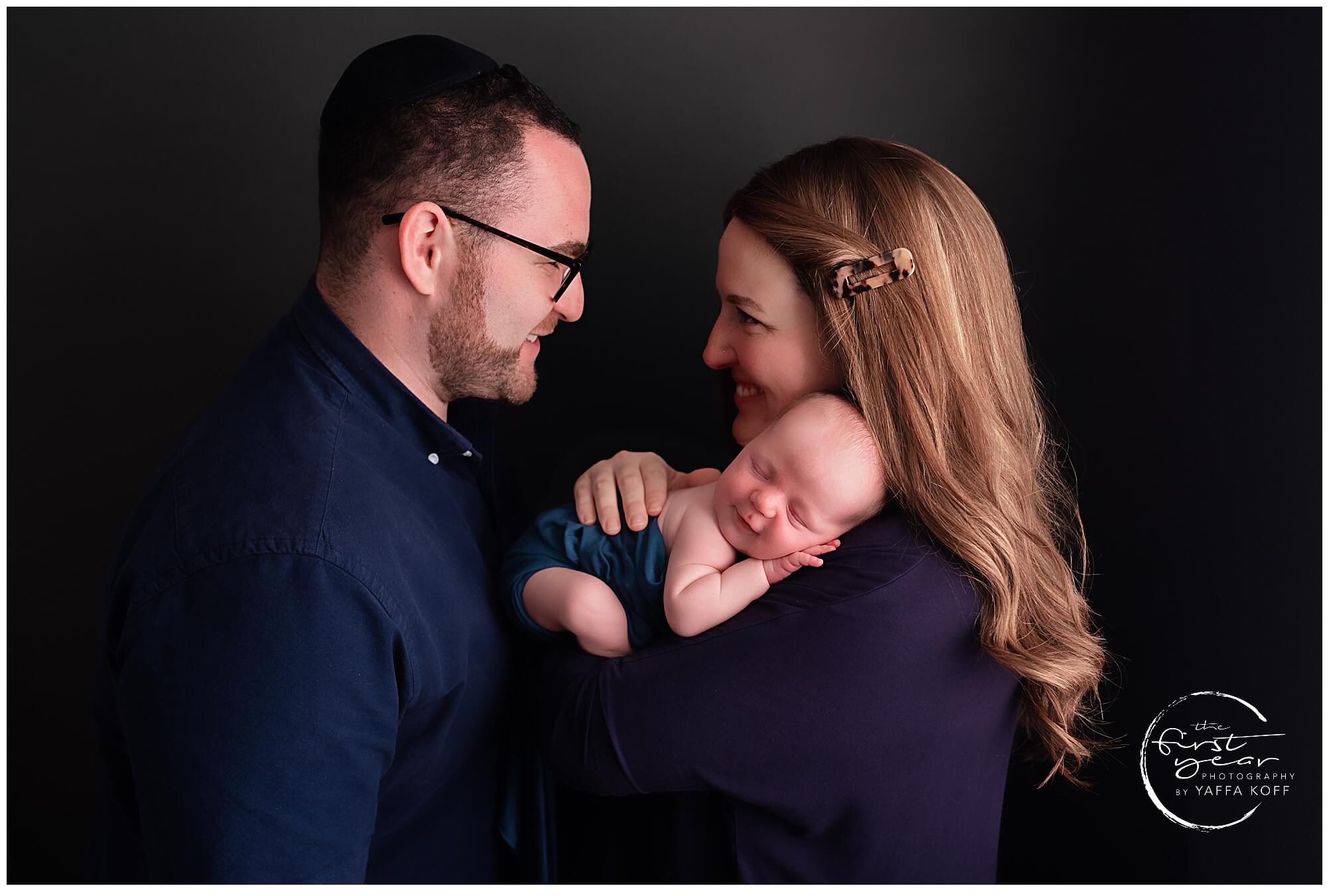 Beautiful newborn portrait of a sleeping baby with parents in a professional studio setting.