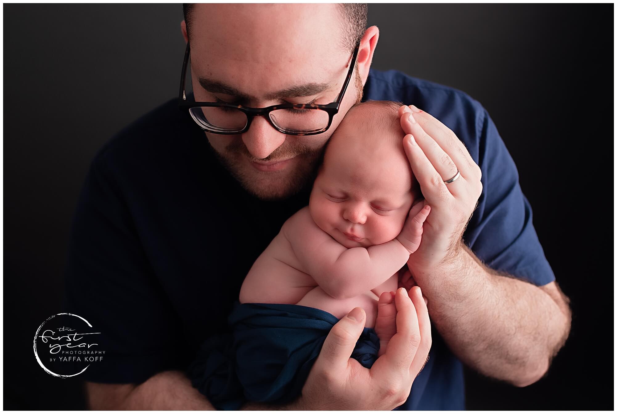 Newborn baby with father in a studio portrait.