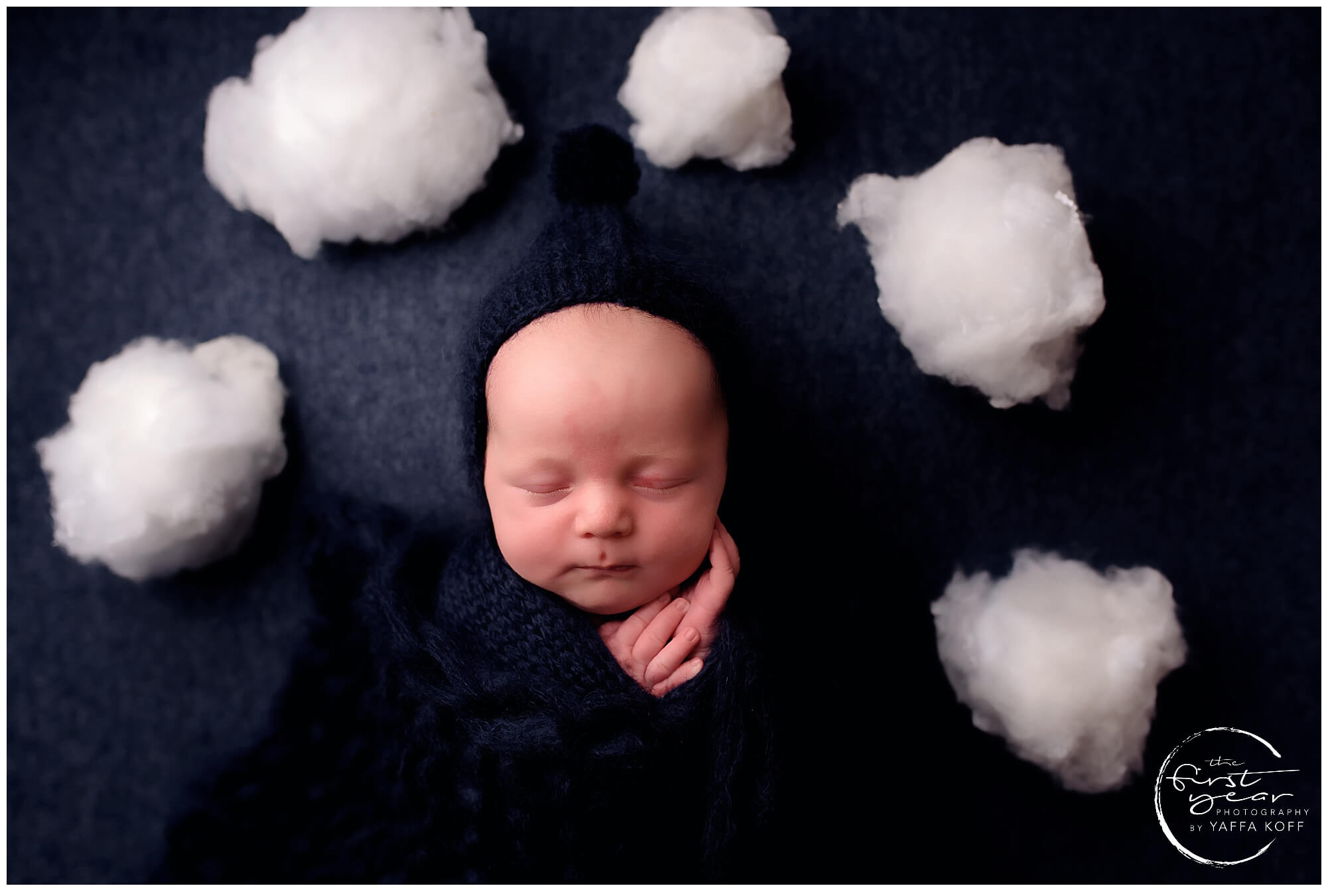 Newborn baby Yehuda peacefully sleeping with cotton cloud props around him.