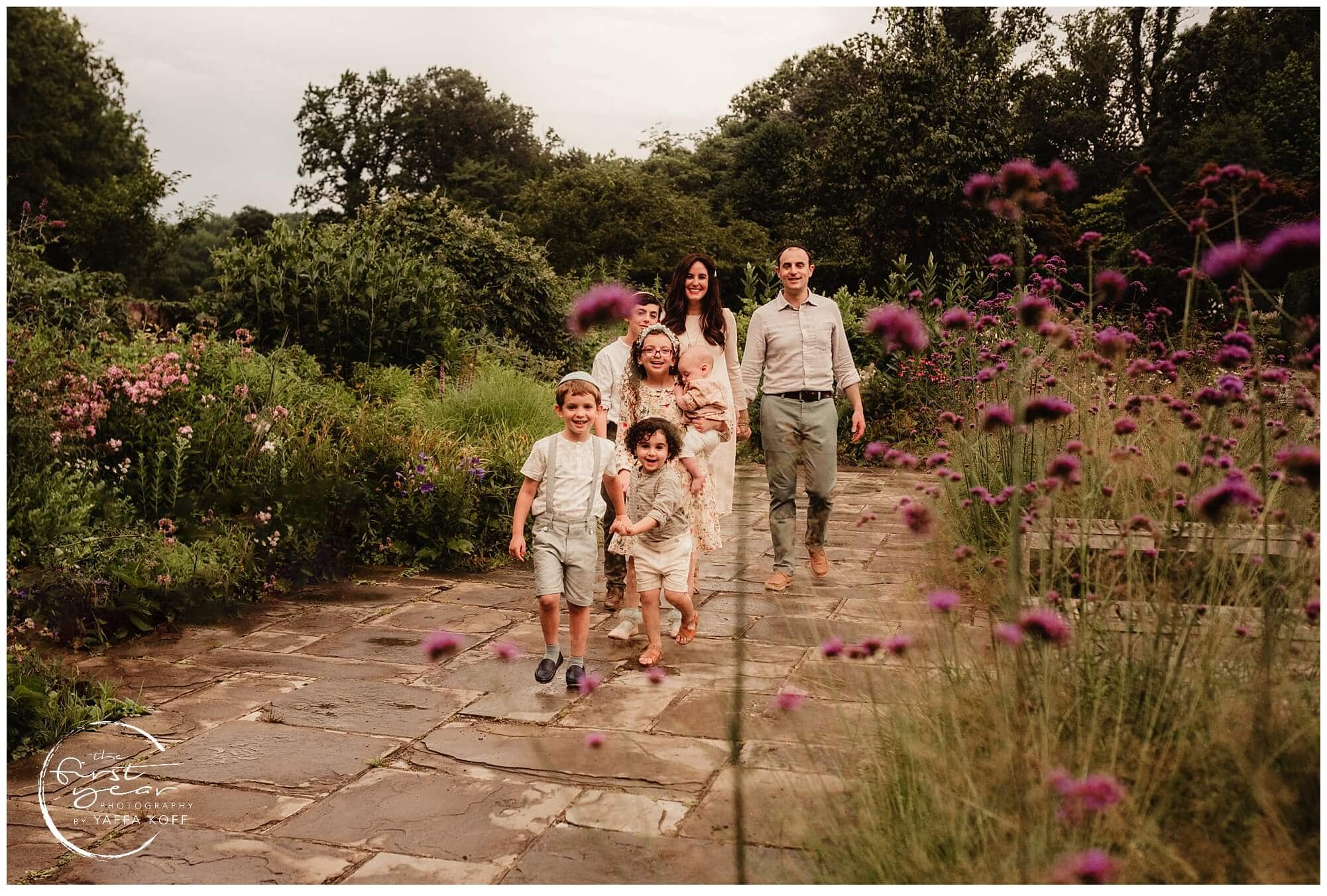 Family outdoor portrait in Silver Spring, MD with parents and children walking on a garden path.