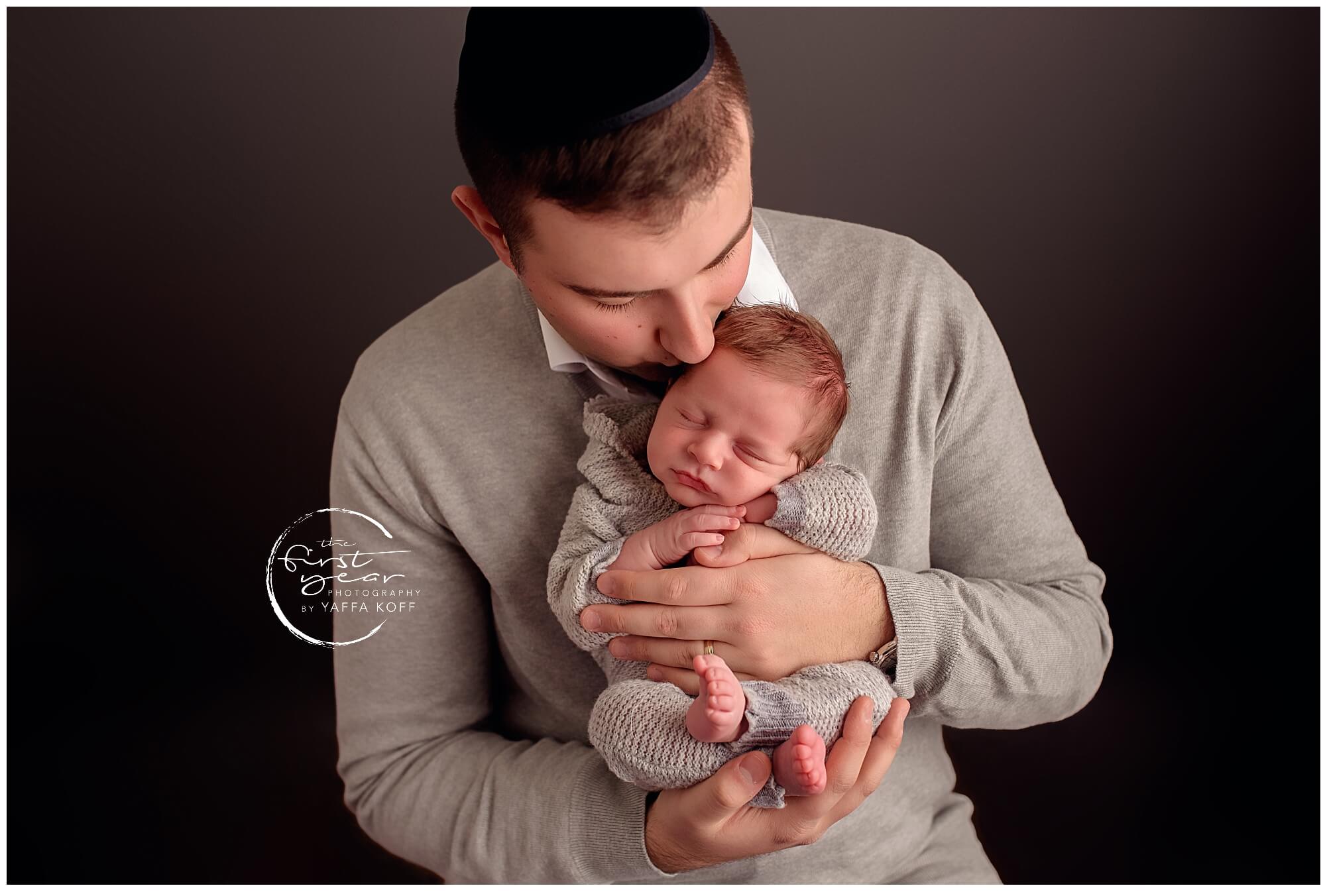 Newborn baby Nathan being held by his father during a Maryland photography session.