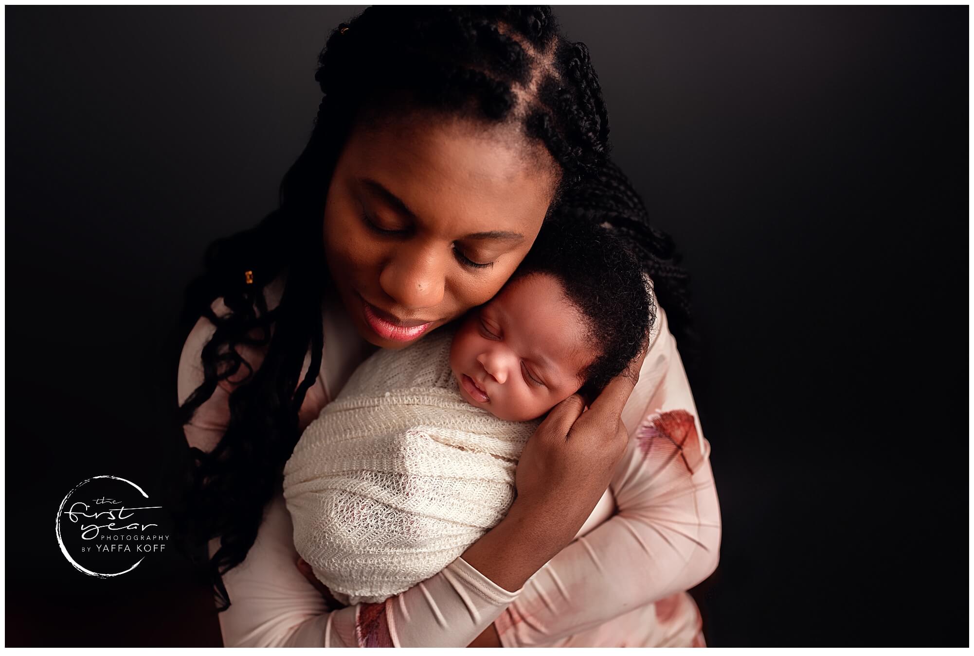 Close-up of mother holding newborn baby in a cozy wrap, capturing tender moments during a newborn ph.