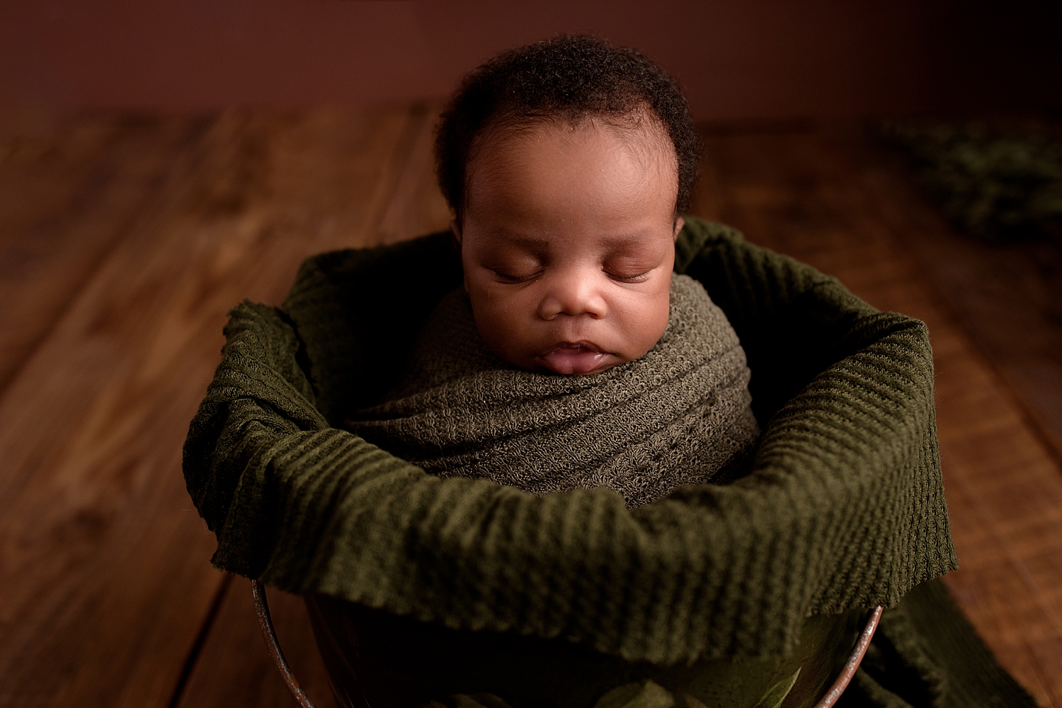 small baby in green blanket after learning How to Prepare for Your Newborn Session
