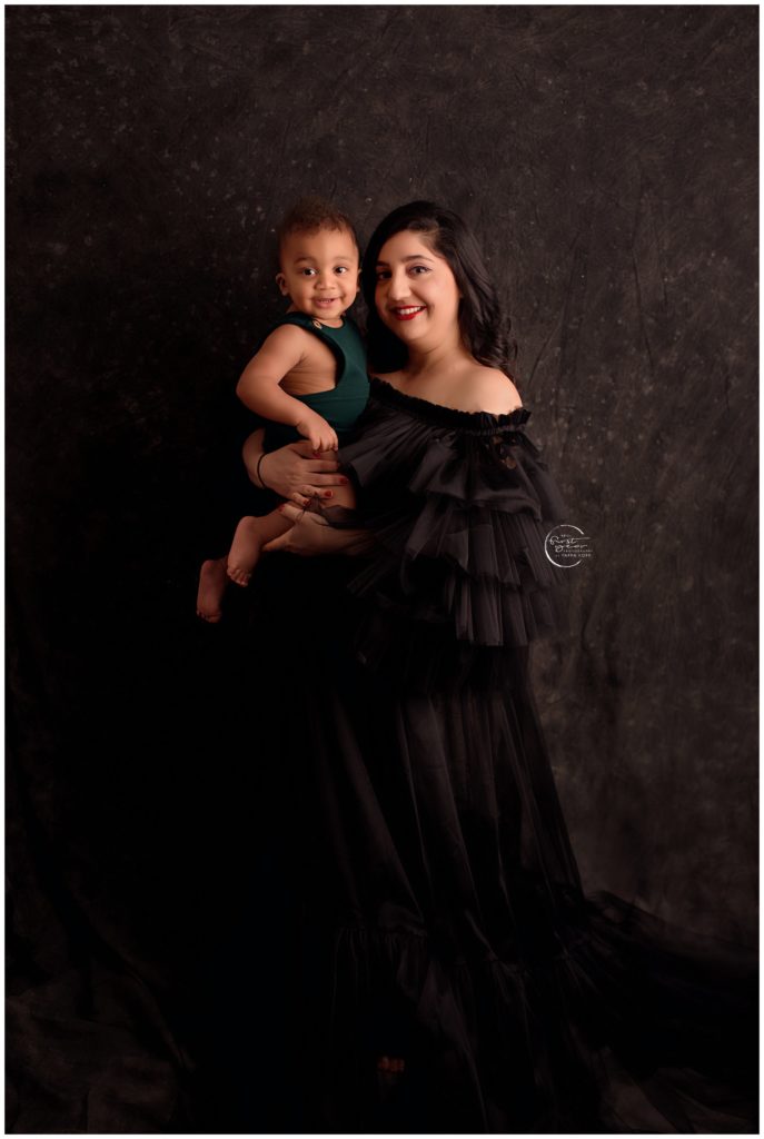 Happy mother holding her smiling baby girl during a cake smash session in Silver Spring, MD.