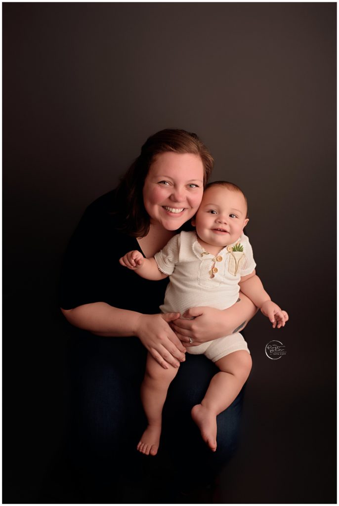 Happy first birthday with a smiling baby and loving mother in a professional studio portrait.