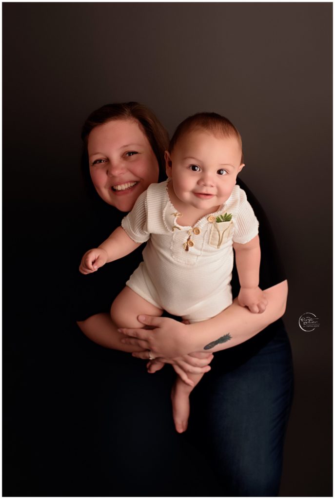 Happy baby celebrating first birthday with mother in studio portrait.