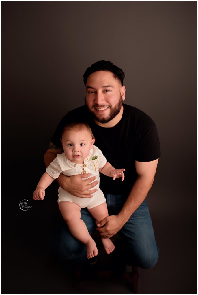 Happy first birthday with a smiling father and baby girl in a studio portrait.