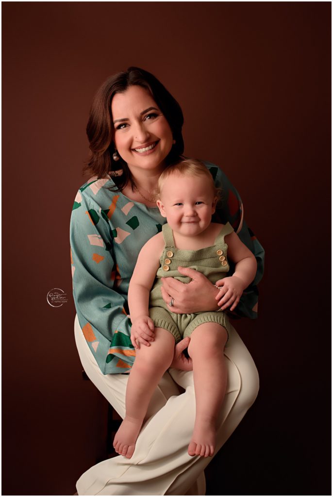 Woman holding smiling baby during birthday cake smash session in Silver Spring, MD.