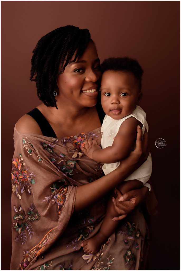 Happy mother holding her smiling baby girl in a warm studio setting.