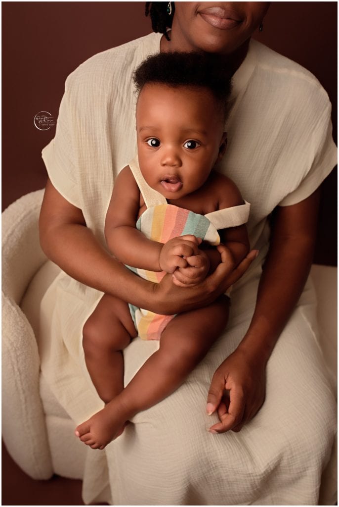 Adorable 6-month-old baby sitting on a woman's lap, capturing a sweet moment during a professional n.