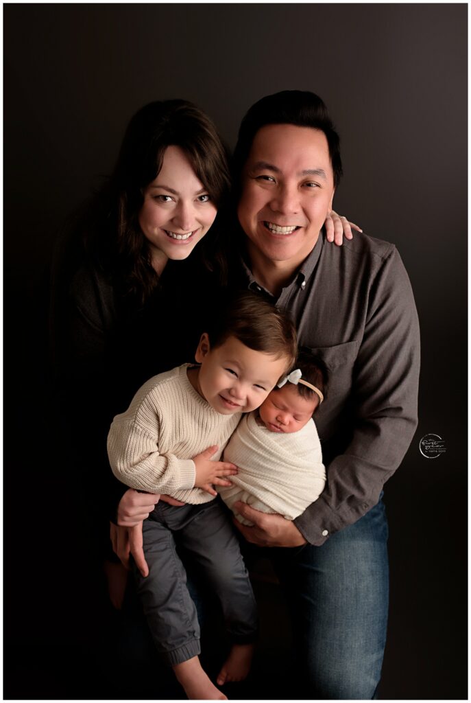 Family with newborn and young children in a studio setting.