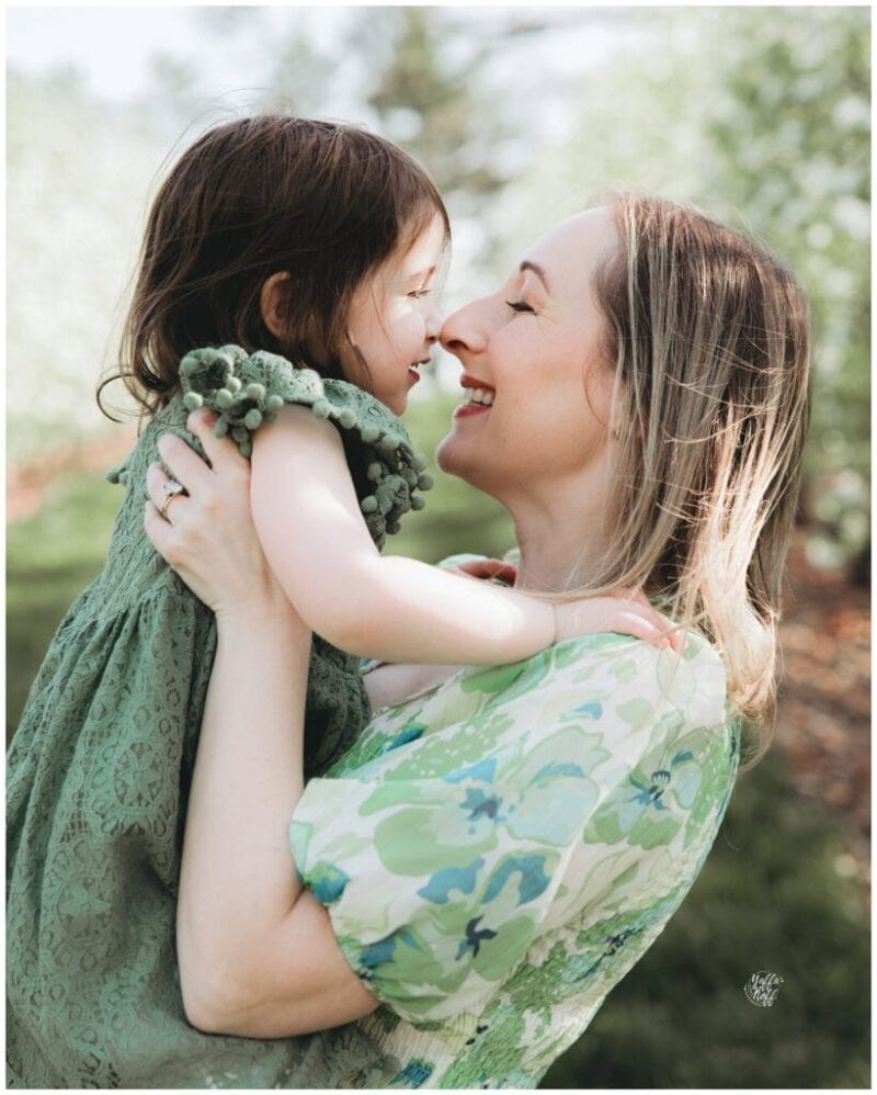 Mother and daughter sharing a joyful moment during a spring outdoor photo shoot.