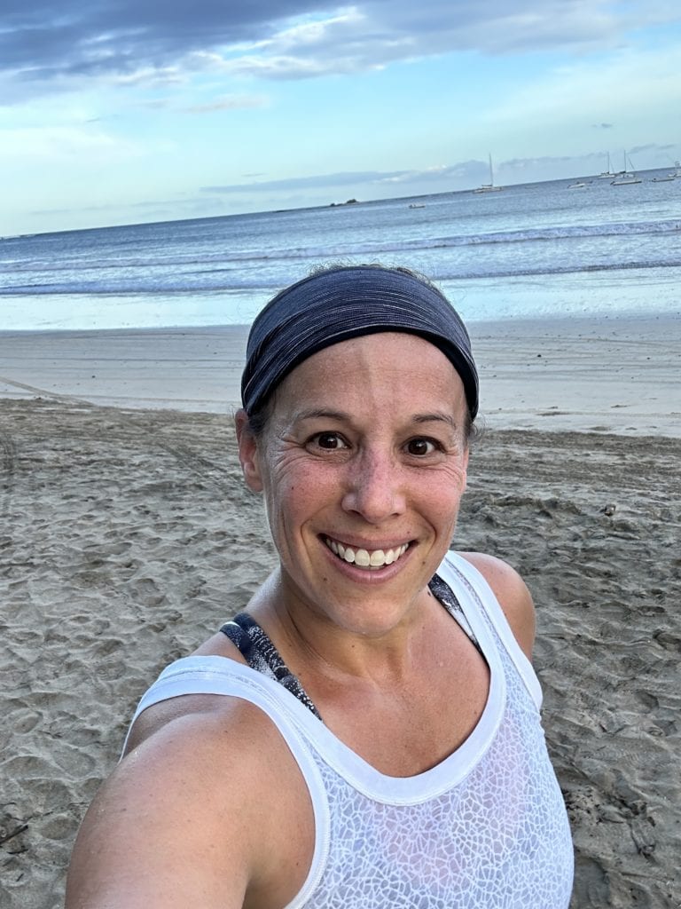 Yoga on the beach, woman smiling, ocean view, relaxing outdoor activity.